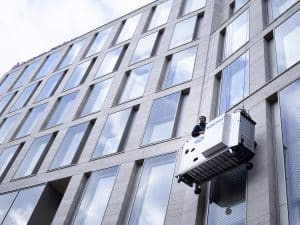 Fassade mit vielen Fenstern und Clean Gebäudereinigern bei der Glasreinigung