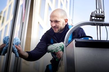 Lächelnder Mitarbeiter Fensterreinigung und Fensterreinigung im Einsatz von Clean.de