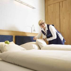 Hotelreinigung / Housekeeping-Mitarbeitering von Clean excellence macht das Bett im Hotel
